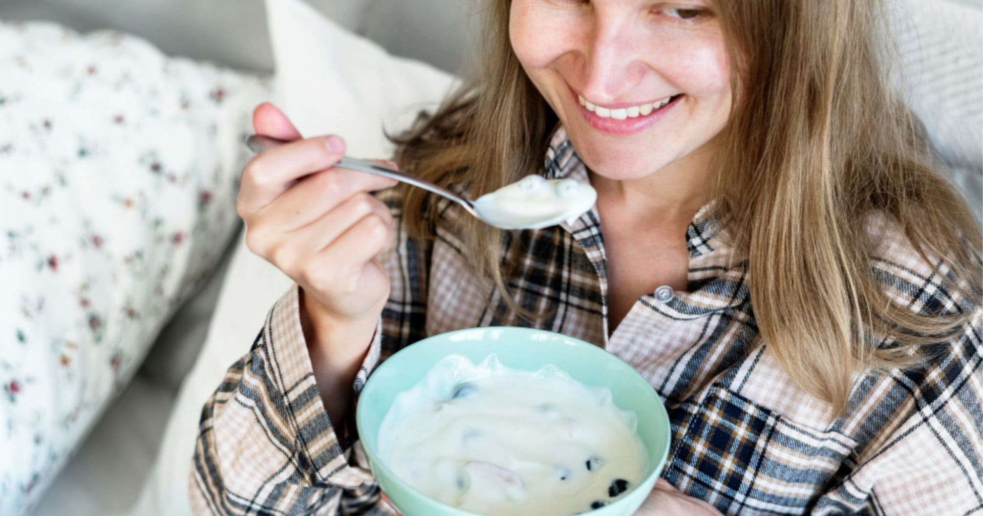 woman eating yoghurt in bed, a soft food suitable during wisdom teeth recovery in Belmont WA